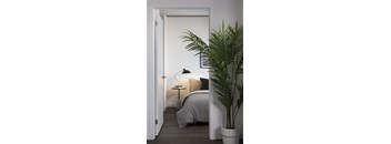A bedroom with a bed, a lamp, and a plant.