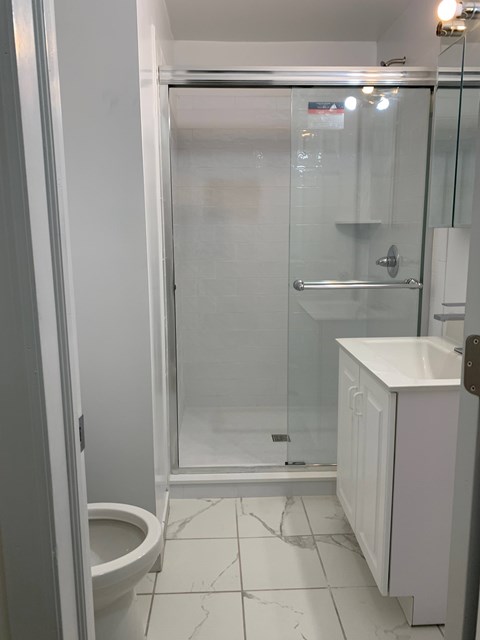A white bathroom with a toilet, sink and shower.