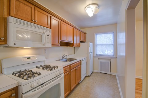 A kitchen with white appliances and wooden cabinets.