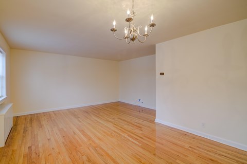 A room with wooden flooring and a chandelier.