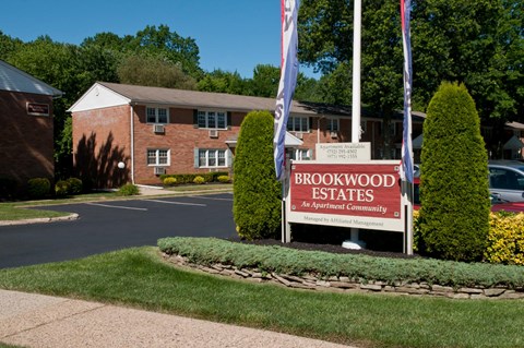 A sign for Brookwood Estates is in front of a brick building.