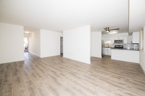 A spacious room with wooden flooring and white walls.