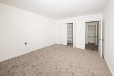 A room with carpeted floor and two doors.