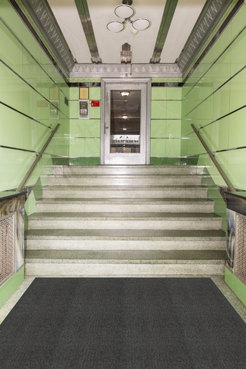 A staircase with a black carpeted floor and green walls.