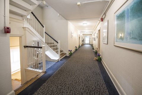 A hallway with a staircase and a painting on the wall.