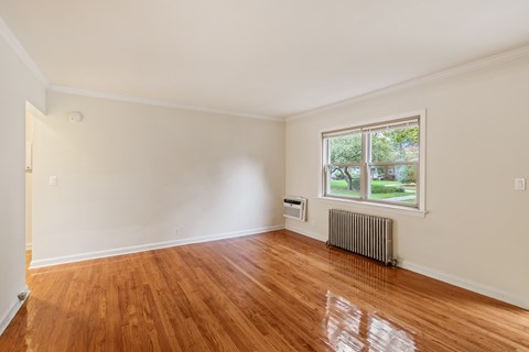 A room with a window and a radiator on the floor.