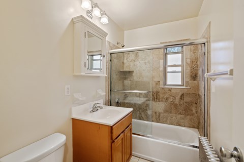 A bathroom with a tub, sink, and mirror.