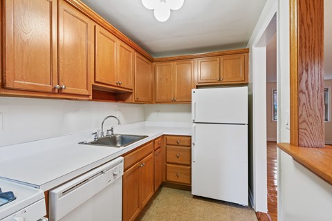 A kitchen with white appliances and wooden cabinets.