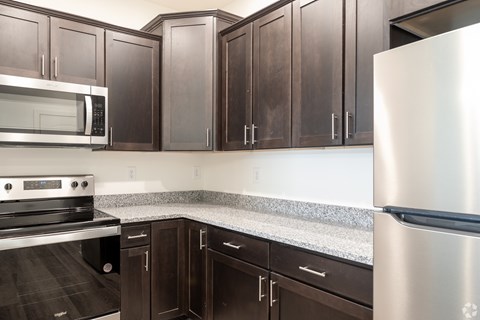 2 Bed 2 Bath - A kitchen with a stainless steel refrigerator, microwave, oven, and cabinets