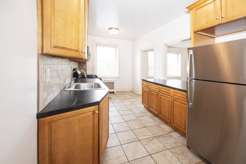 A kitchen with wooden cabinets and a stainless steel refrigerator.
