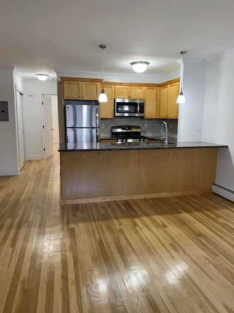 A kitchen with wooden floors and cabinets.