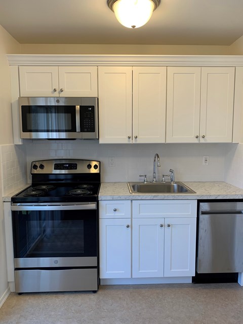 A kitchen with white cabinets and a black stove top oven.