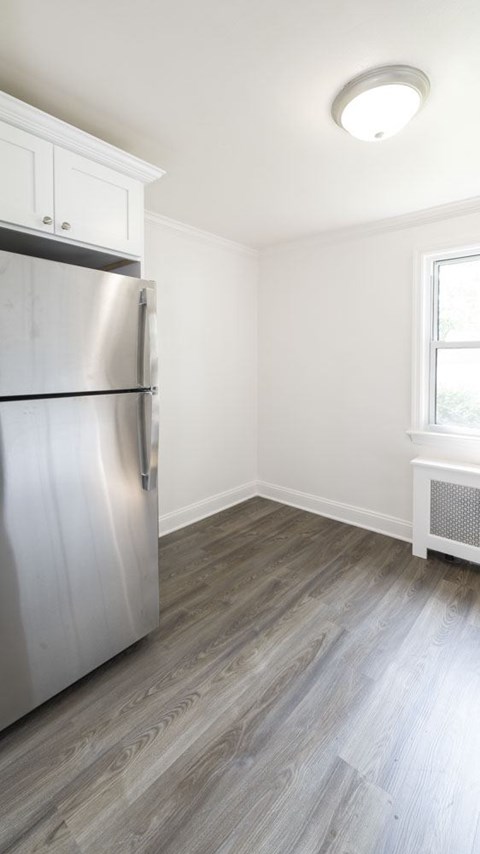 A kitchen with a stainless steel refrigerator and wooden flooring.