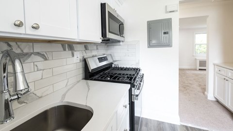 A kitchen with a stove, sink, and microwave.
