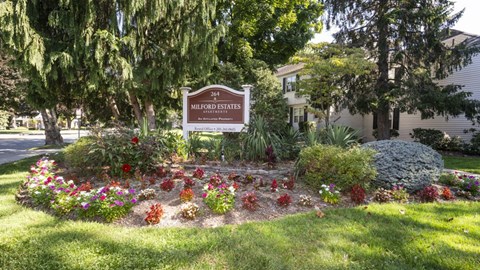 A sign for Millford Estates is in front of a flower bed.