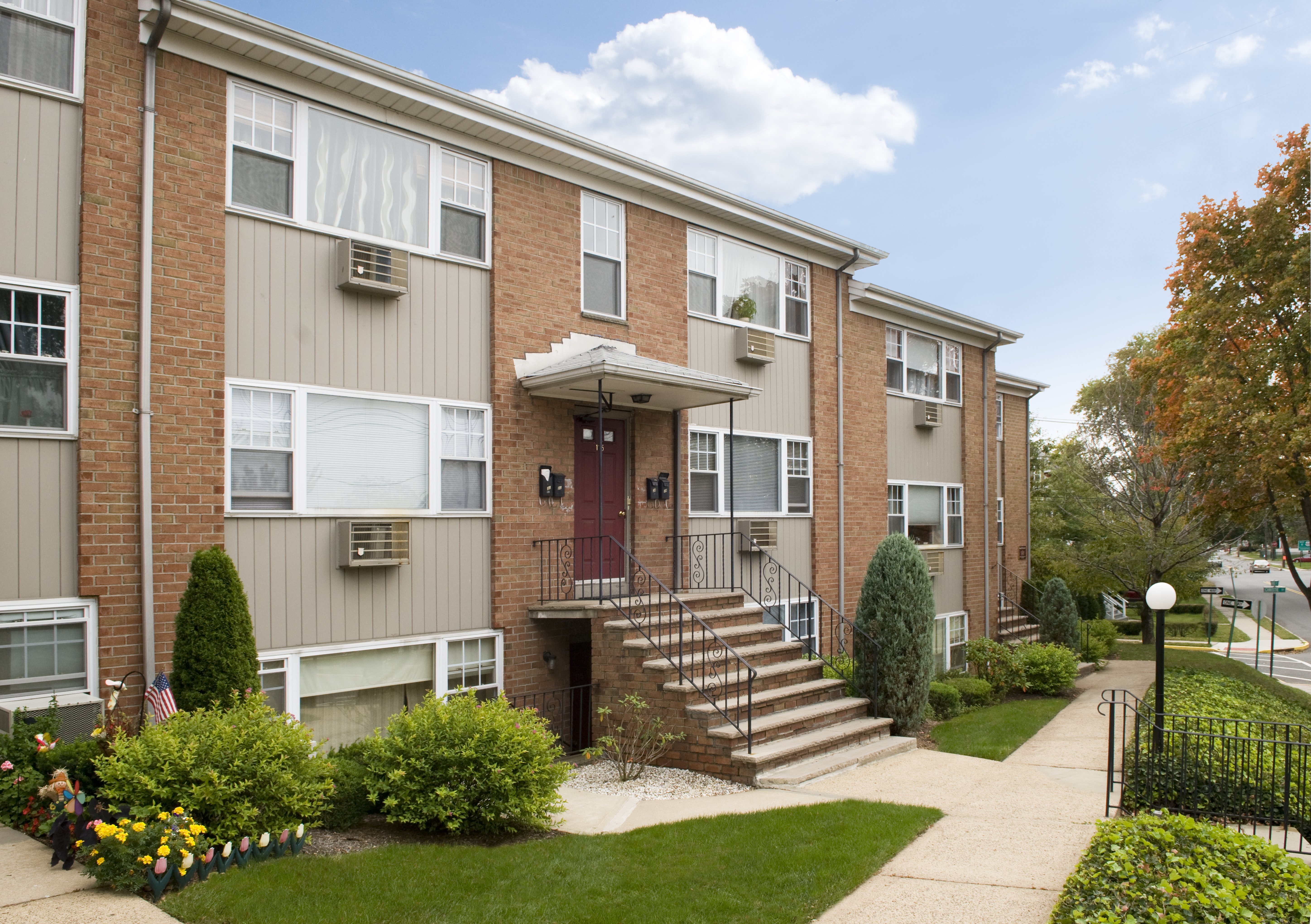 Apartment building with a red door and a small front yard.