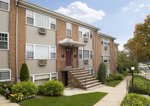 Apartment building with a red door and a small front yard.