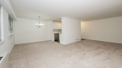 A spacious room with a carpeted floor and a chandelier hanging from the ceiling.