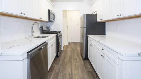 A kitchen with white cabinets and a black fridge.