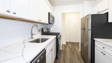 A kitchen with white cabinets and a black fridge.