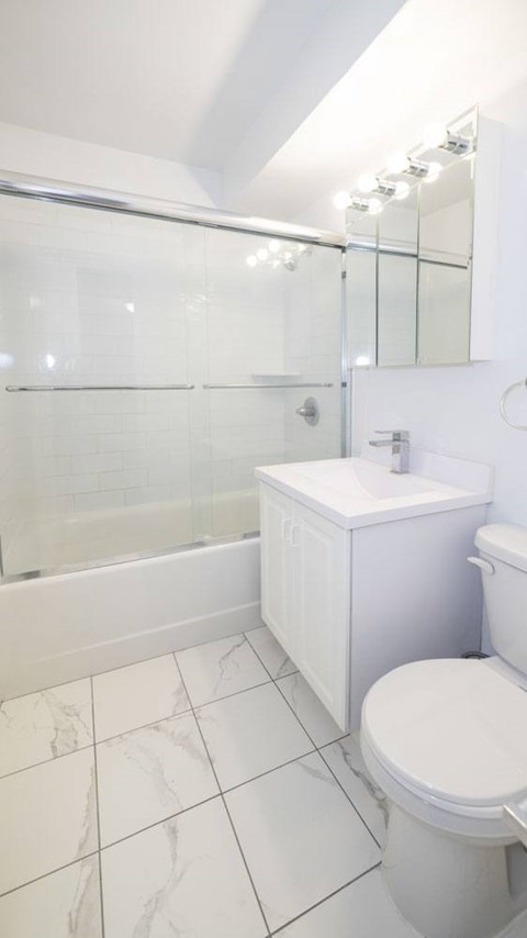 A white toilet sits next to a white sink in a white bathroom.