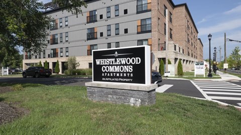 A sign for Whistlewood Commons is in front of a building.