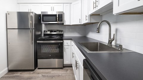 A modern kitchen with a stainless steel refrigerator, oven, and microwave.