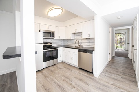 A kitchen with white cabinets and a black countertop.