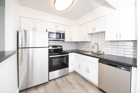 A kitchen with white cabinets and a black countertop.