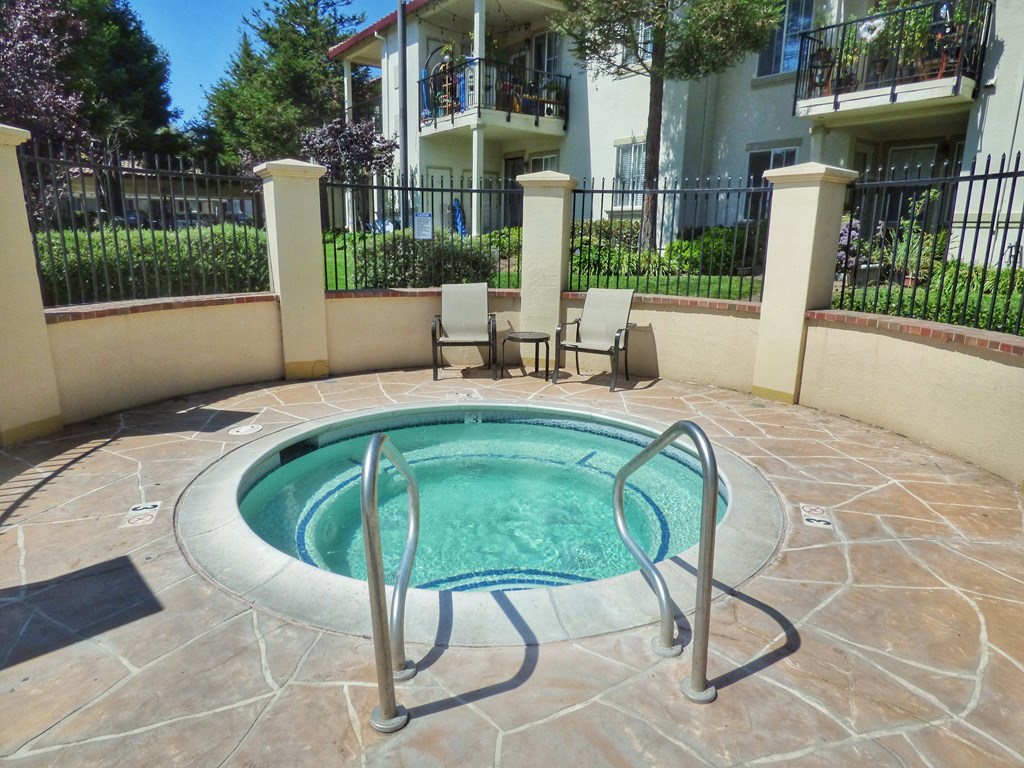 a small hot tub in a pool in front of an apartment building