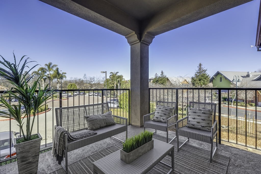 A balcony with a bench, cushions, and a potted plant.