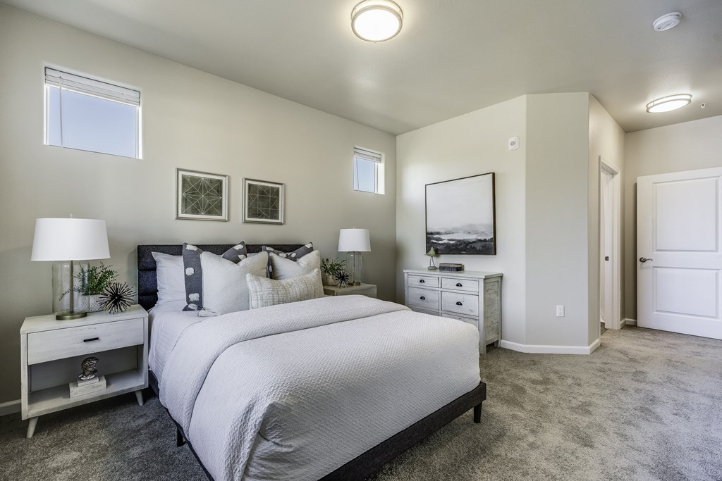 A bedroom with a large bed, nightstand, and a painting on the wall.