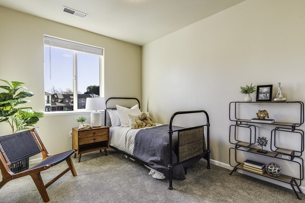 A bedroom with a bed, chair, and shelf.
