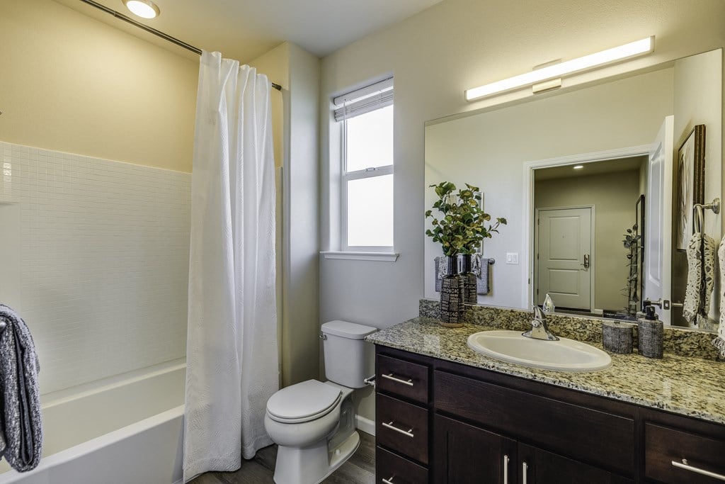 A white toilet sits in a bathroom with a white shower curtain.