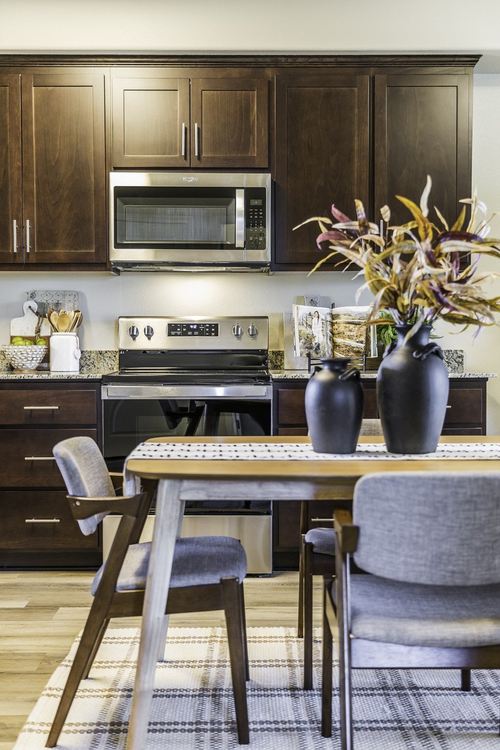 A kitchen with a table and chairs and a microwave above the stove.