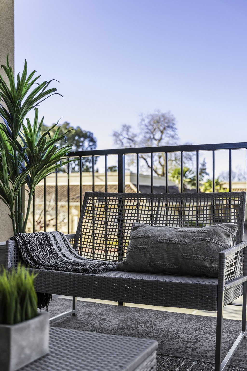 A black metal patio set with a grey cushion and a grey throw on it.