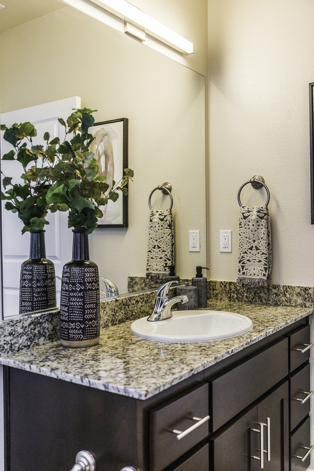 A bathroom with a sink, mirror, and towel racks.