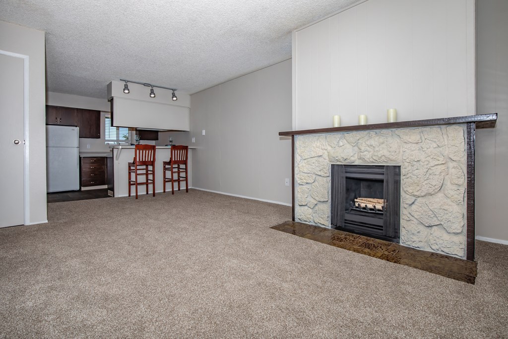 an empty living room with a fireplace and a kitchen at Lincoln Village Apartments, Spokane Washington