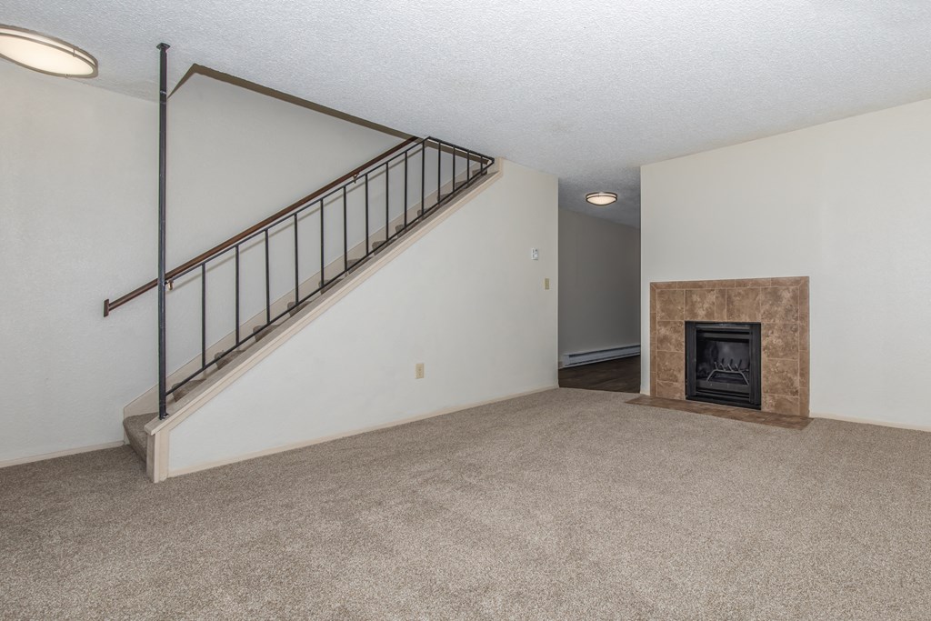 an empty living room with a staircase and a fireplace at Lincoln Village Apartments, Spokane