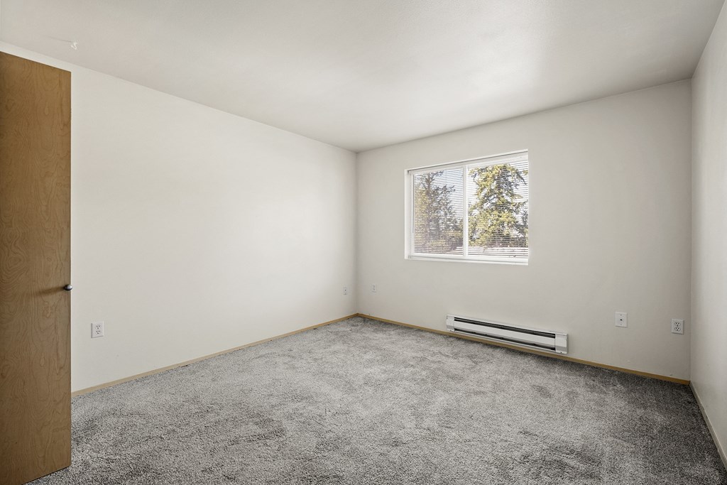 a bedroom with white walls and carpet at Mill Pond Apartments, Washington