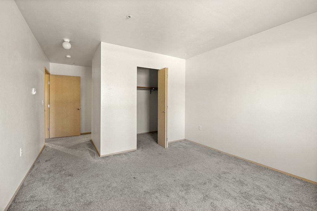 a bedroom with white walls and grey carpet at Mill Pond Apartments, Auburn