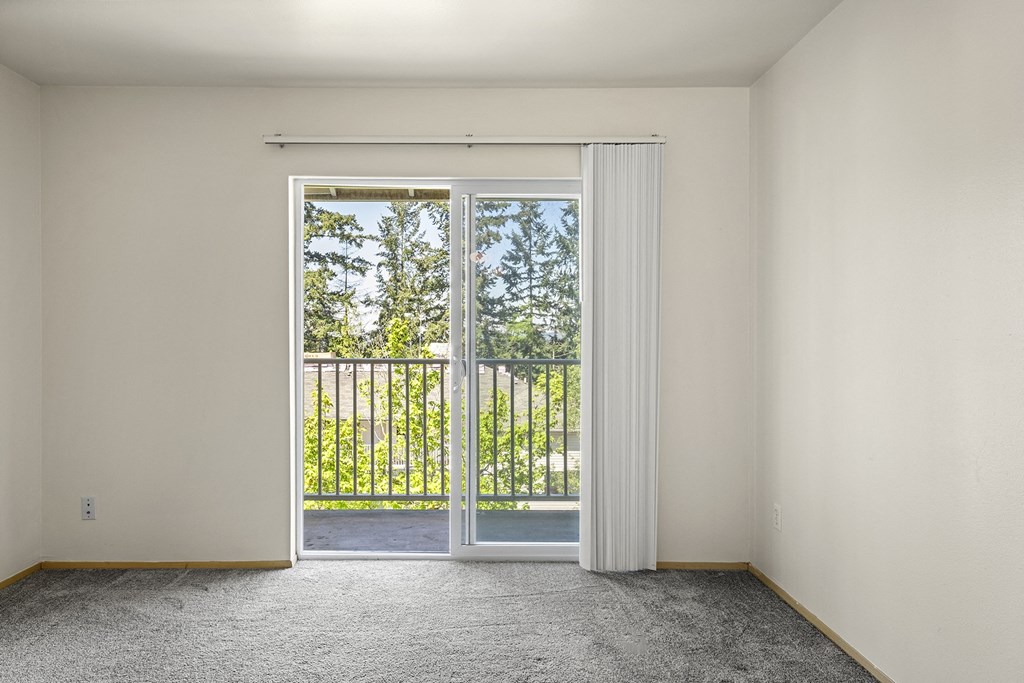 a bedroom with a sliding glass door and a balconyat Mill Pond Apartments, Auburn, WA