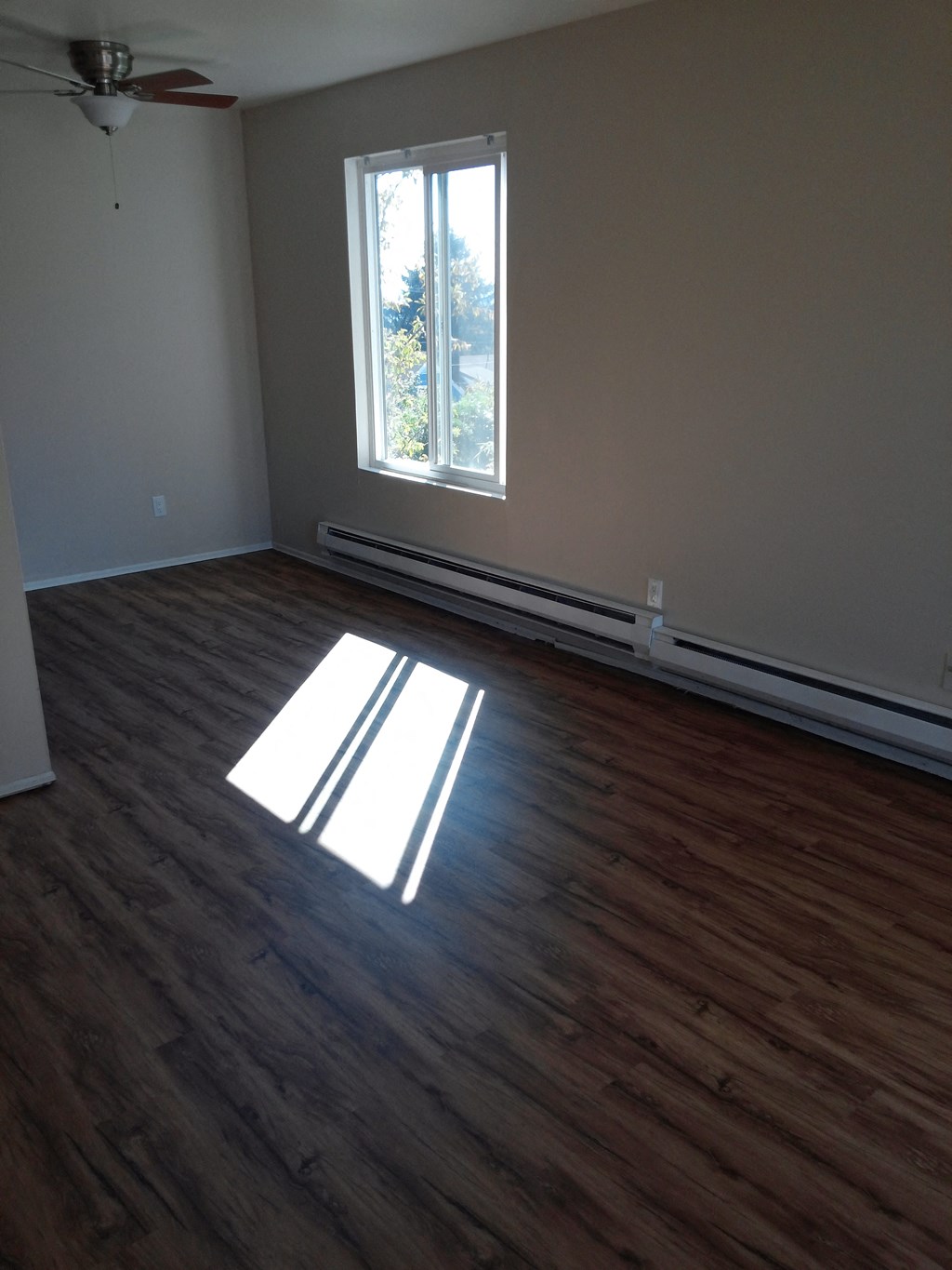 an empty living room with wooden floors and a window
