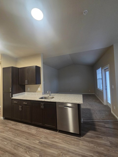 A kitchen with dark wood cabinets and a stainless steel dishwasher.