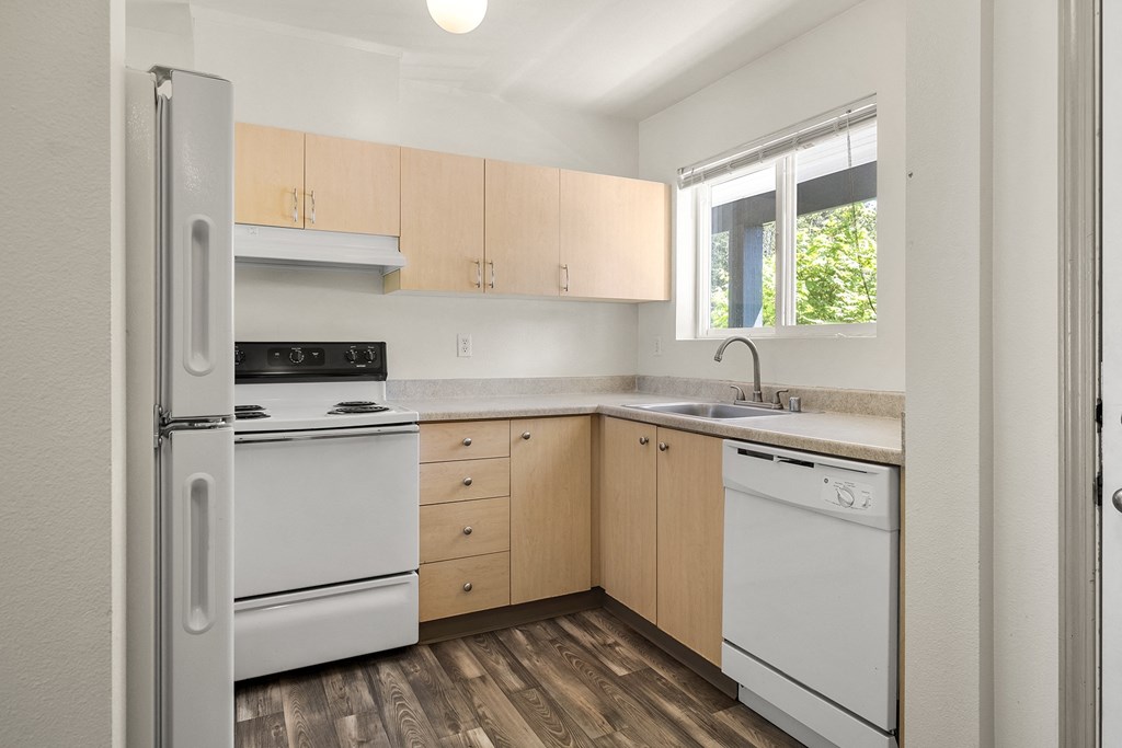 a kitchen with white appliances and wooden cabinets at Mill Pond Apartments, Auburn, WA 98092