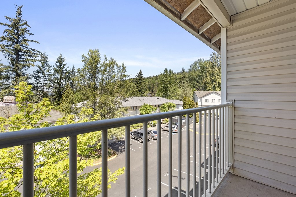 a balcony with a view of a parking lot and trees at Mill Pond Apartments, Auburn