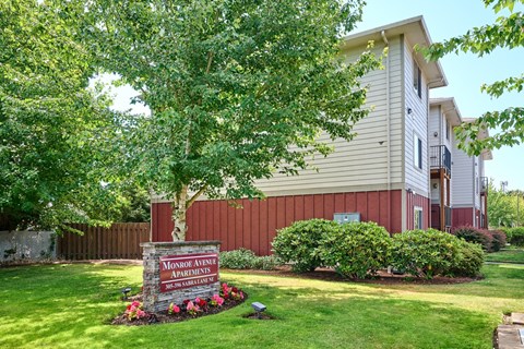 Property entrance sign with seasonal flowers and landscaping at Monroe Avenue Apartments, Salem, 97301