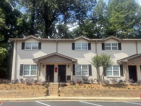 A two-story house with a red door and a small front yard at Waverly Manor Townhomes, Norcross, GA 30071
