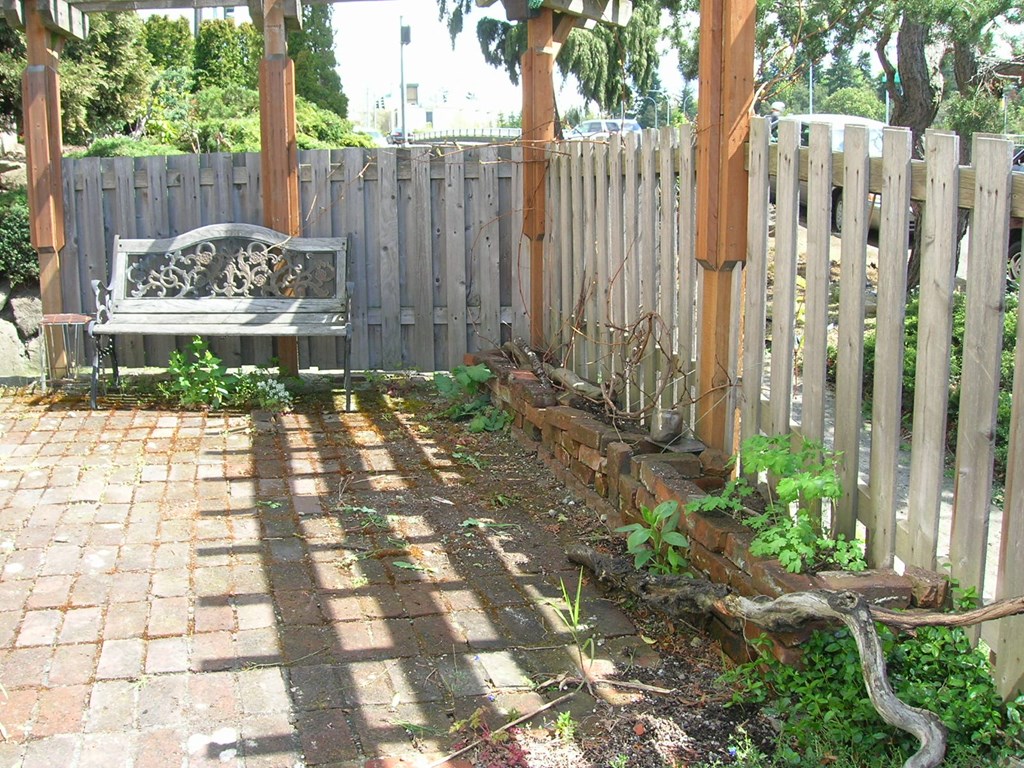 a bench in a garden next to a white fence