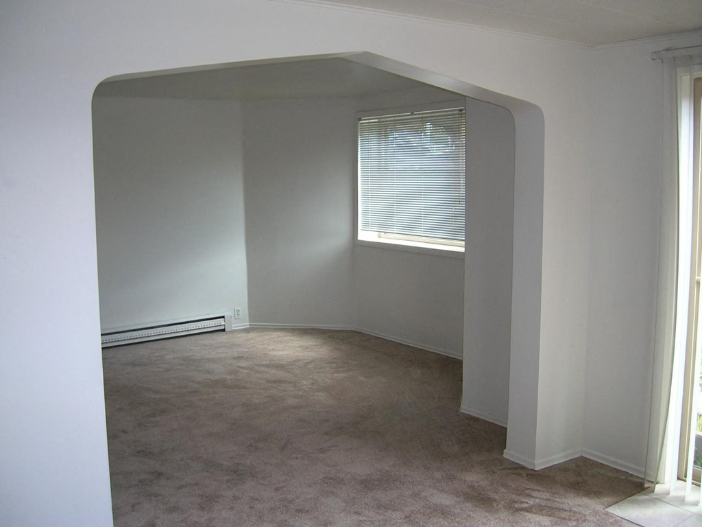 an empty room with a window and white walls